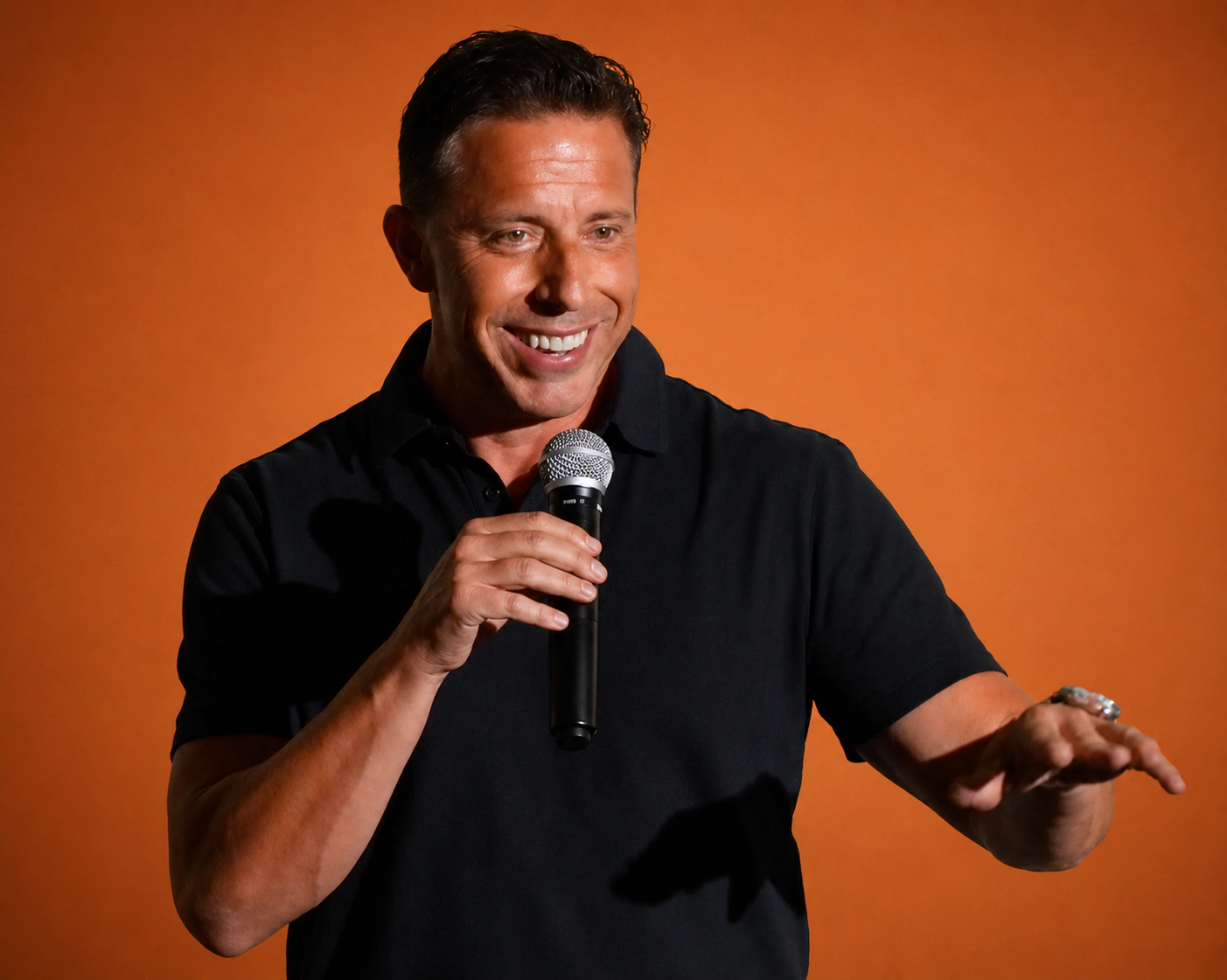 Aaron Bare smiling while speaking into a microphone