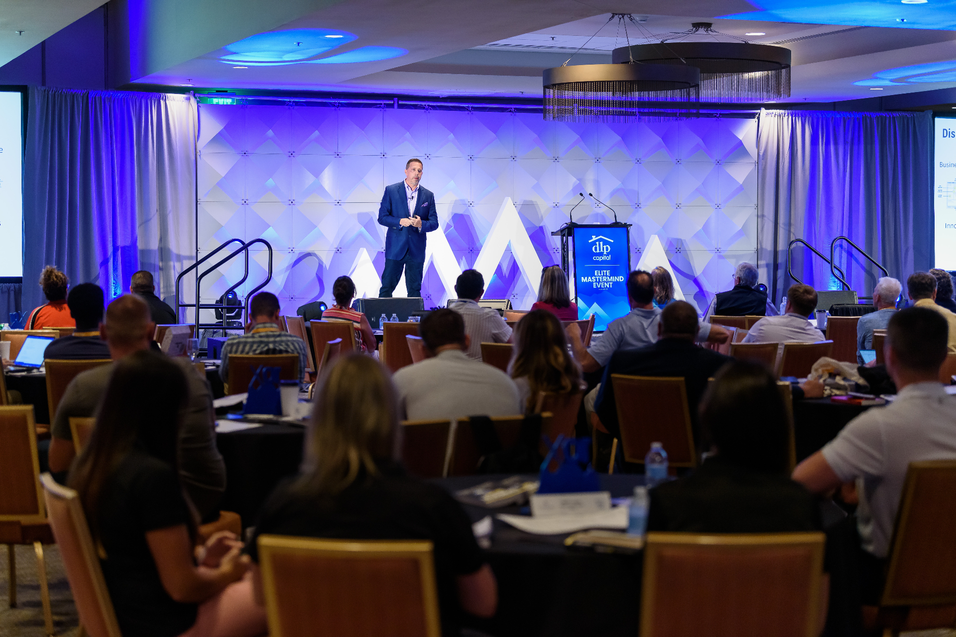 Aaron Bare speaking on stage in front of an audience at the DLP Capital Elite Mastermind event